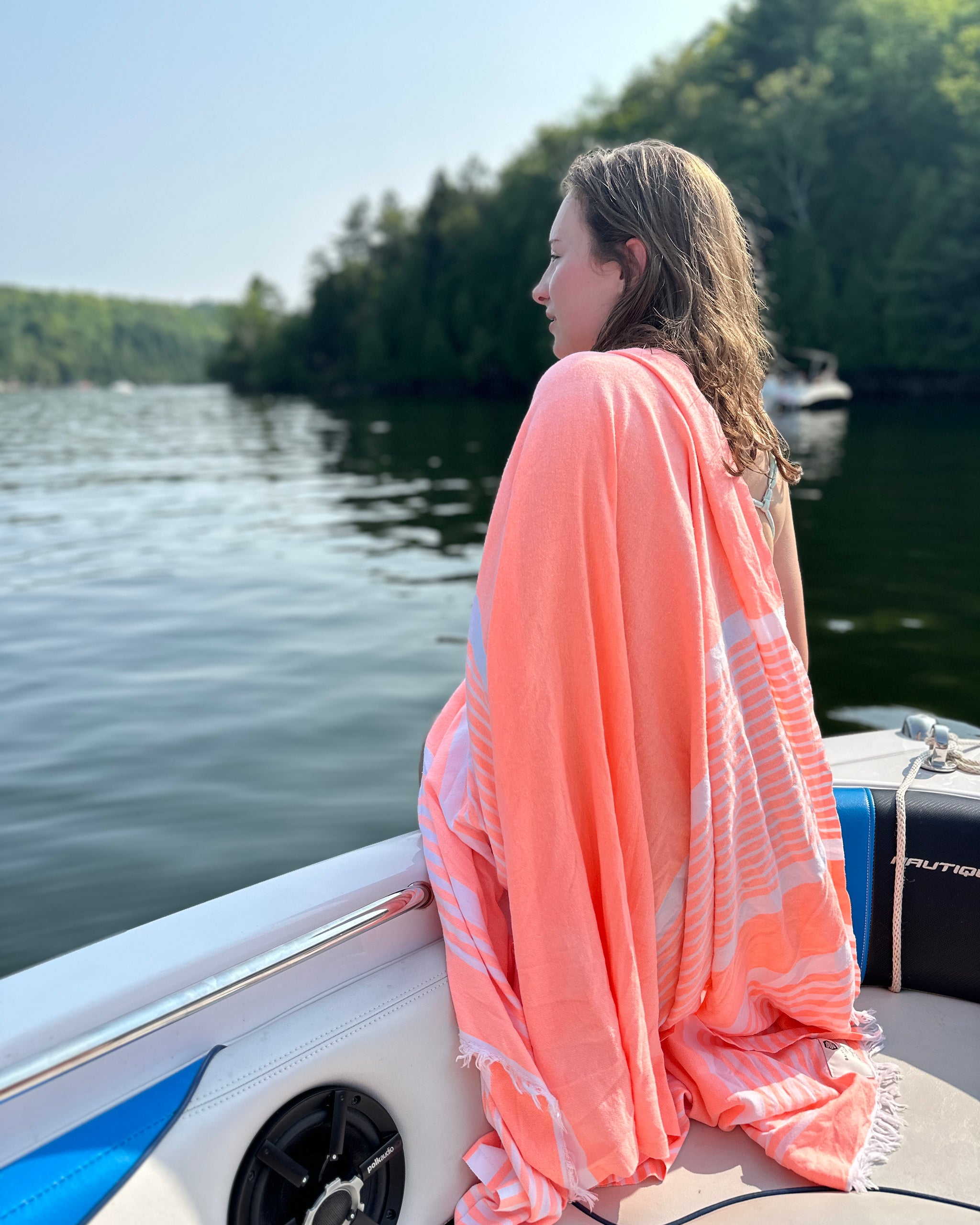 A woman on a boat wrapped in a pink Bonbon towel