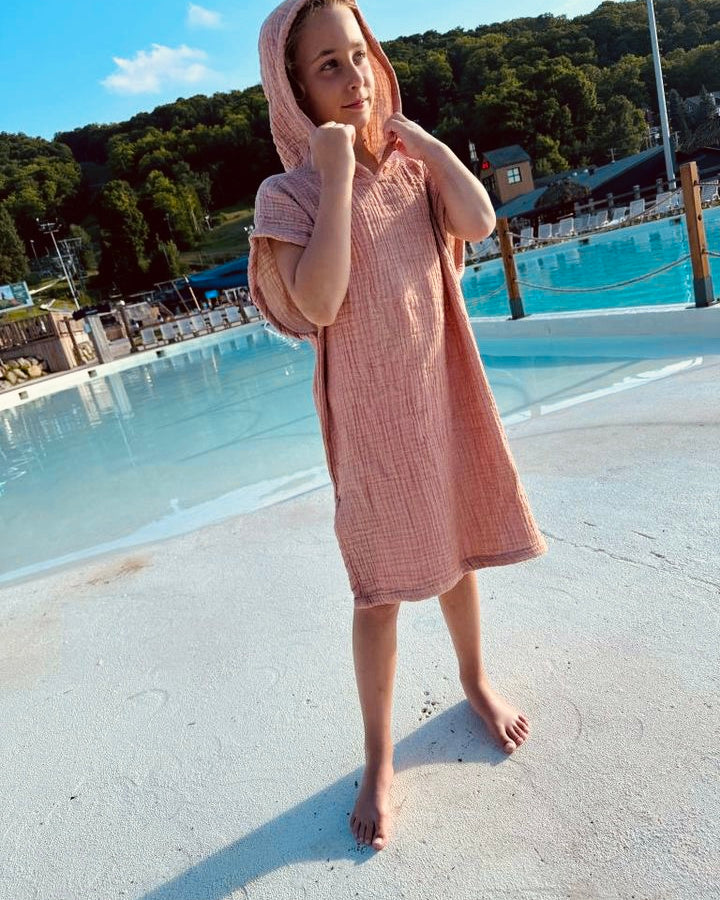 A child in a pink Mini Poncho by the pool