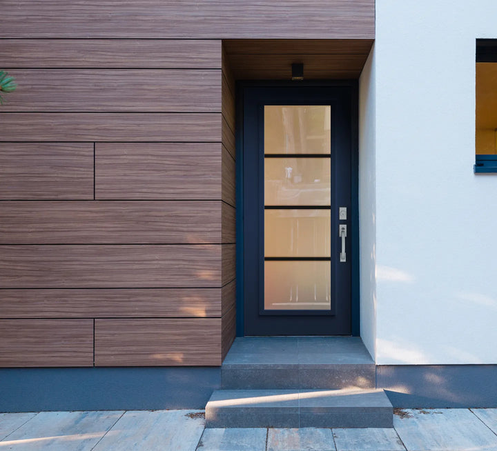 Navy blue front door with divided frosted glass, between wood cladding and a white wall
