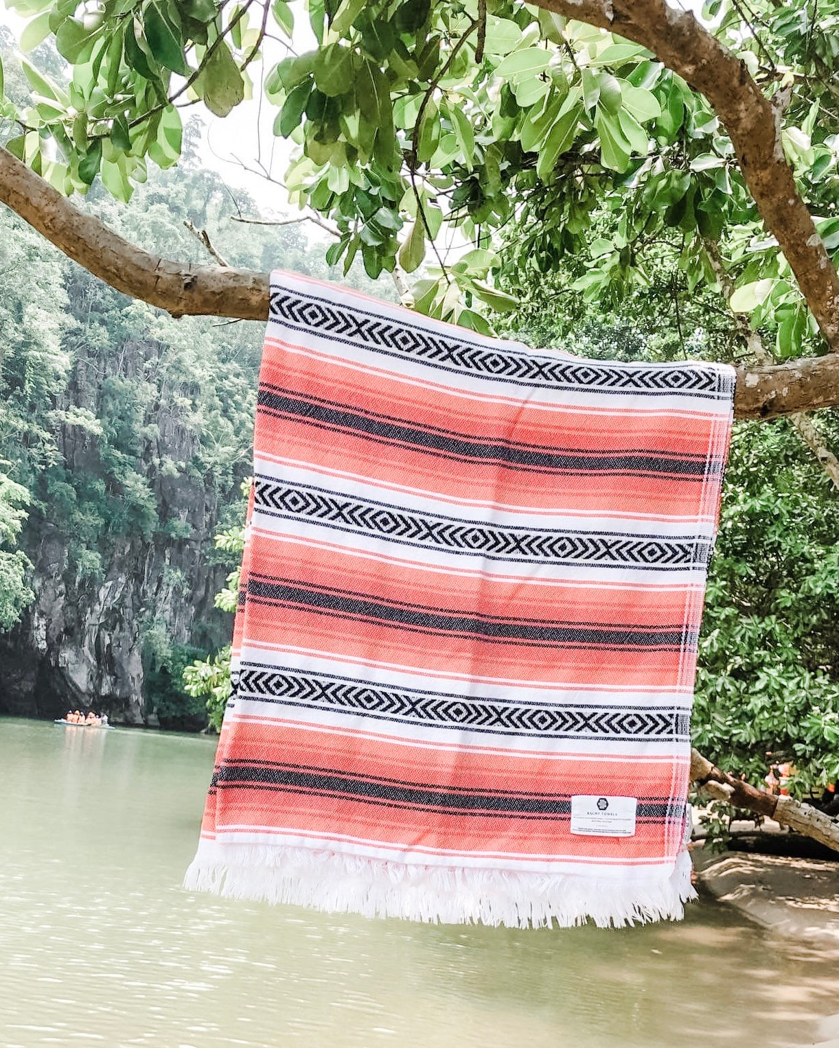 A Rae towel hanging over the water by a riverbank