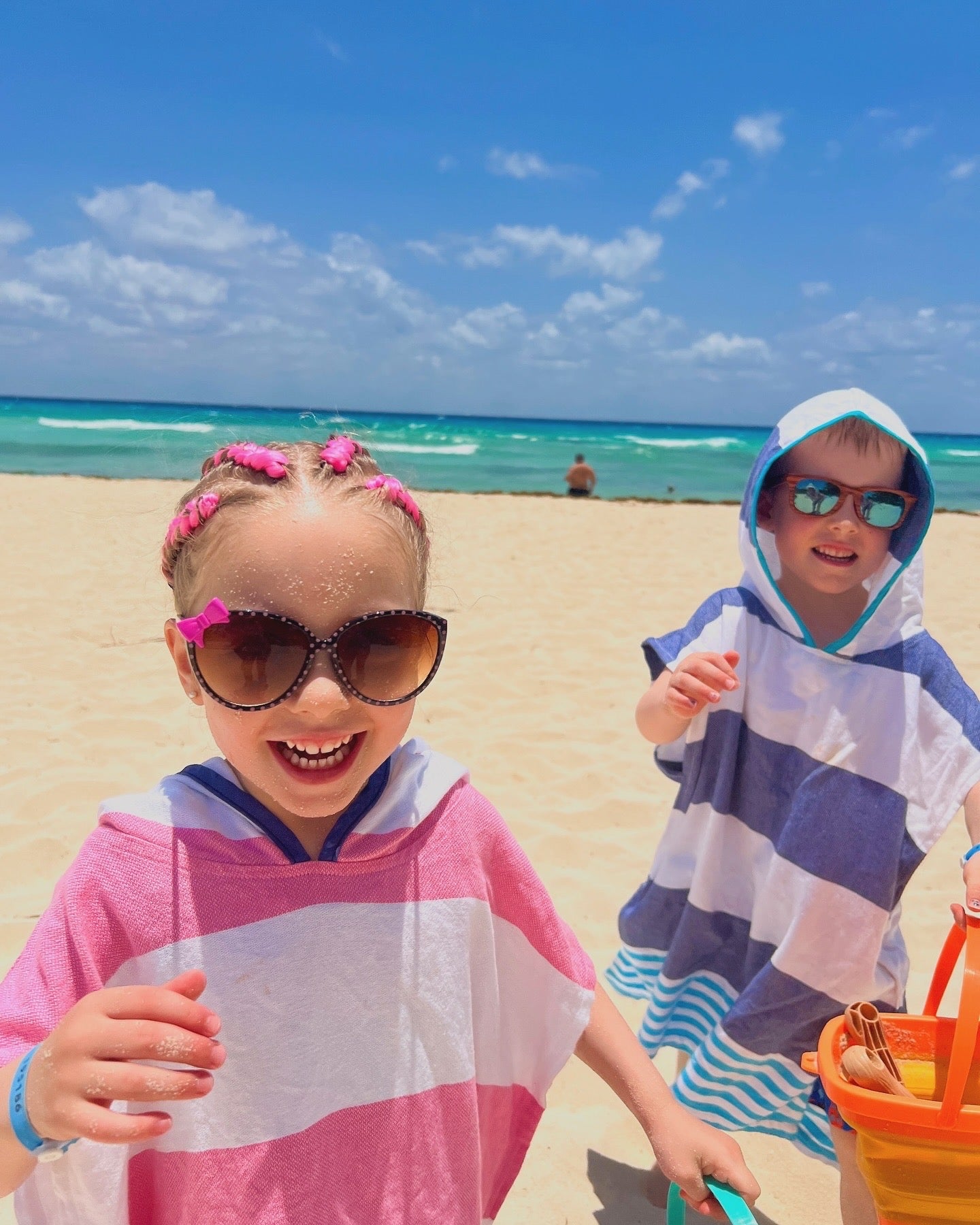 Two children in striped Zoe ponchos at the beach