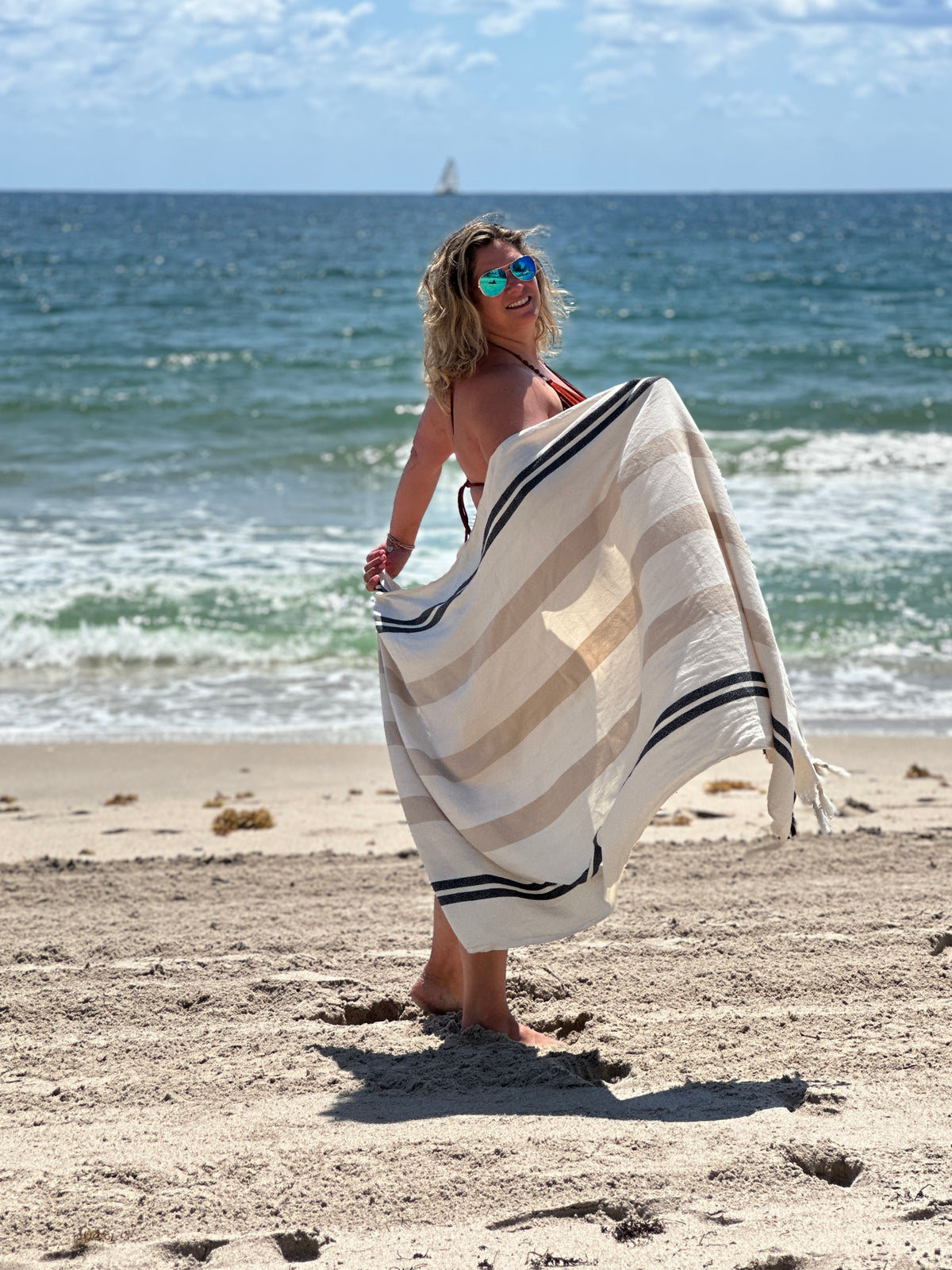 Woman happy at the beach with her Balmy Sienna towel