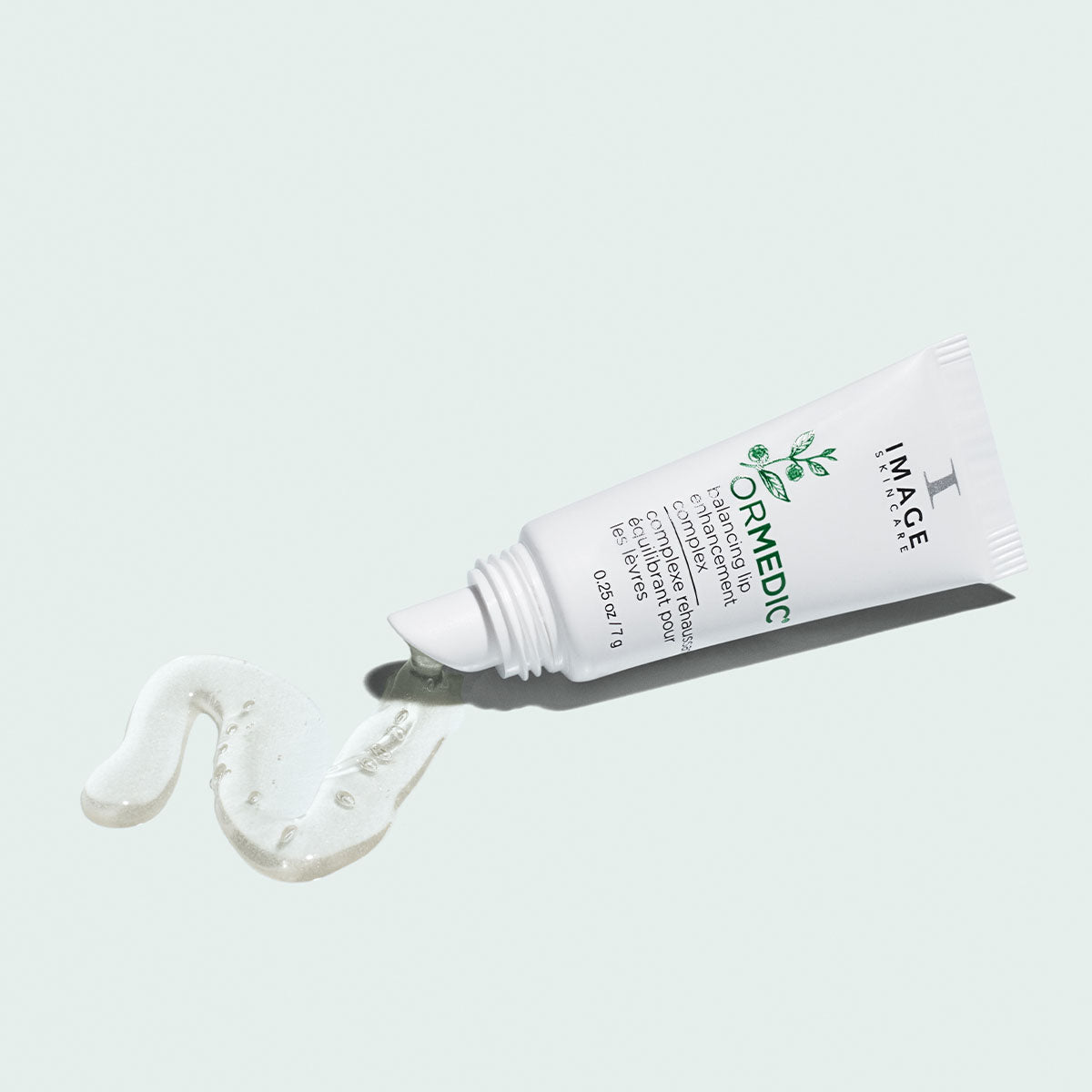 Tube ORMEDIC complexe équilibrant pour les lèvres d’Image Skincare d’où s’écoule un gel transparent, fond pâle