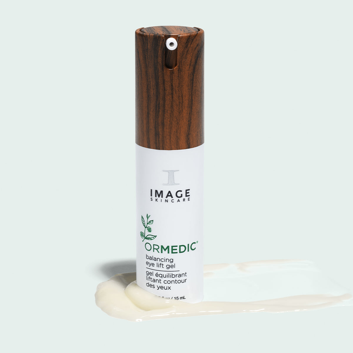 Flacon ORMEDIC gel équilibrant pour les yeux d’Image Skincare debout sur une traînée de gel crémeux, fond pâle