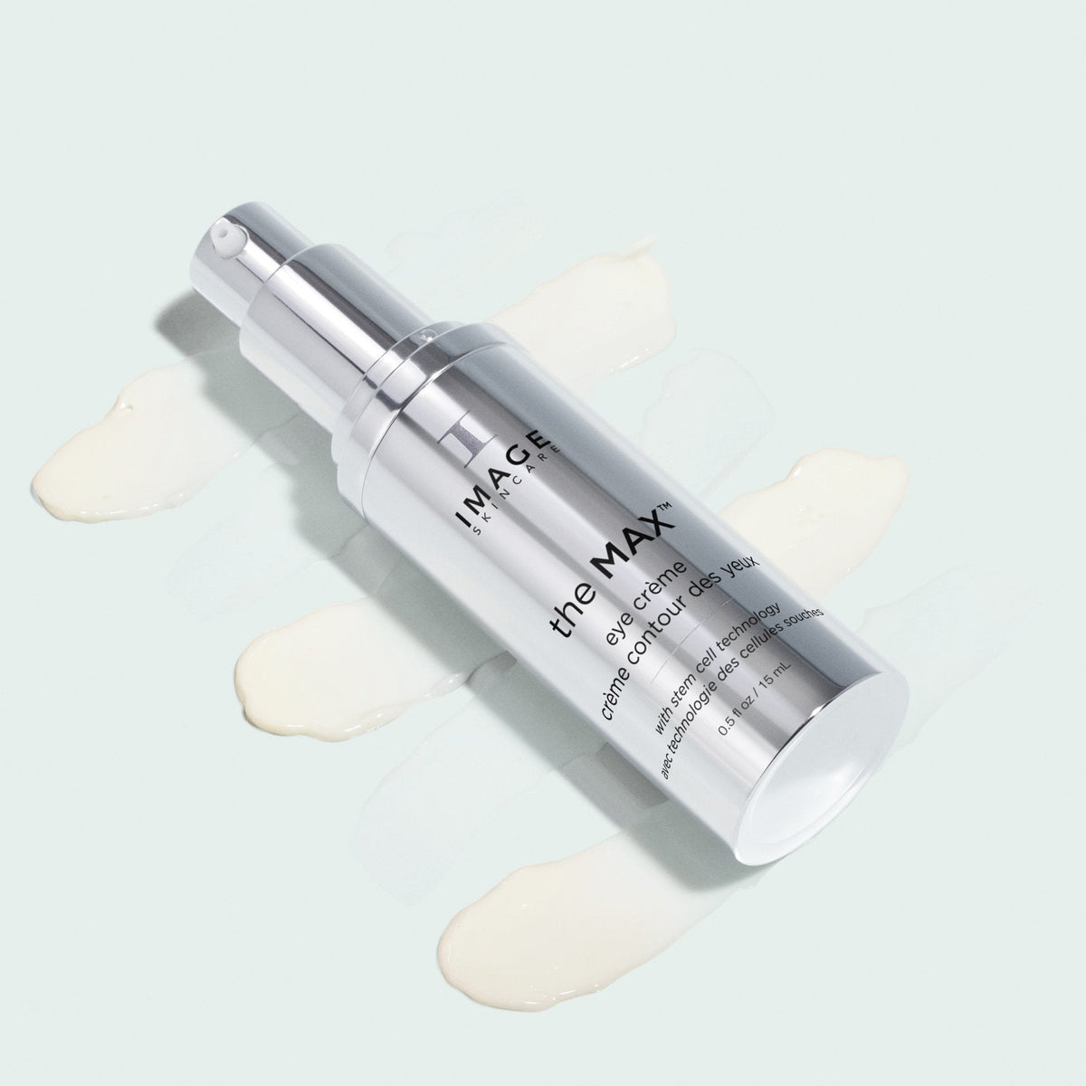 Flacon argenté the MAX crème contour des yeux d’Image Skincare couché sur des traînées de crème ivoire, fond pâle