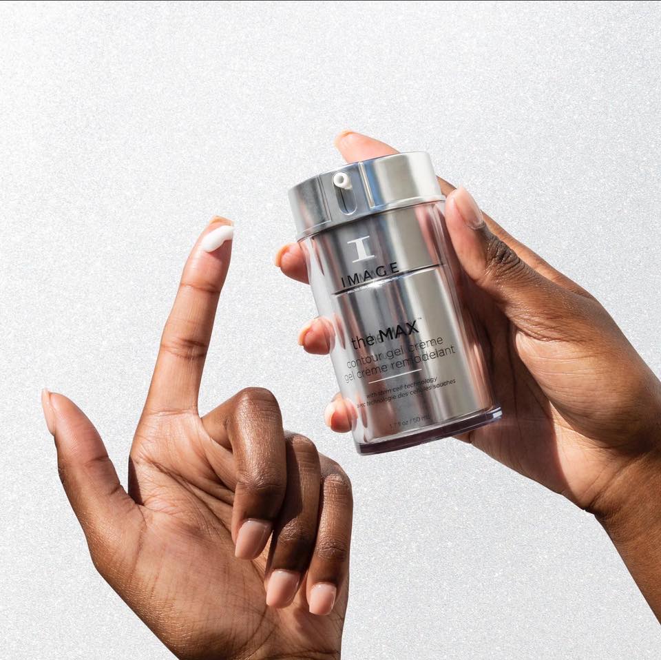 Une main tient le flacon argenté the MAX gel crème remodelant d’Image Skincare, une noisette de crème sur l’index de l’autre