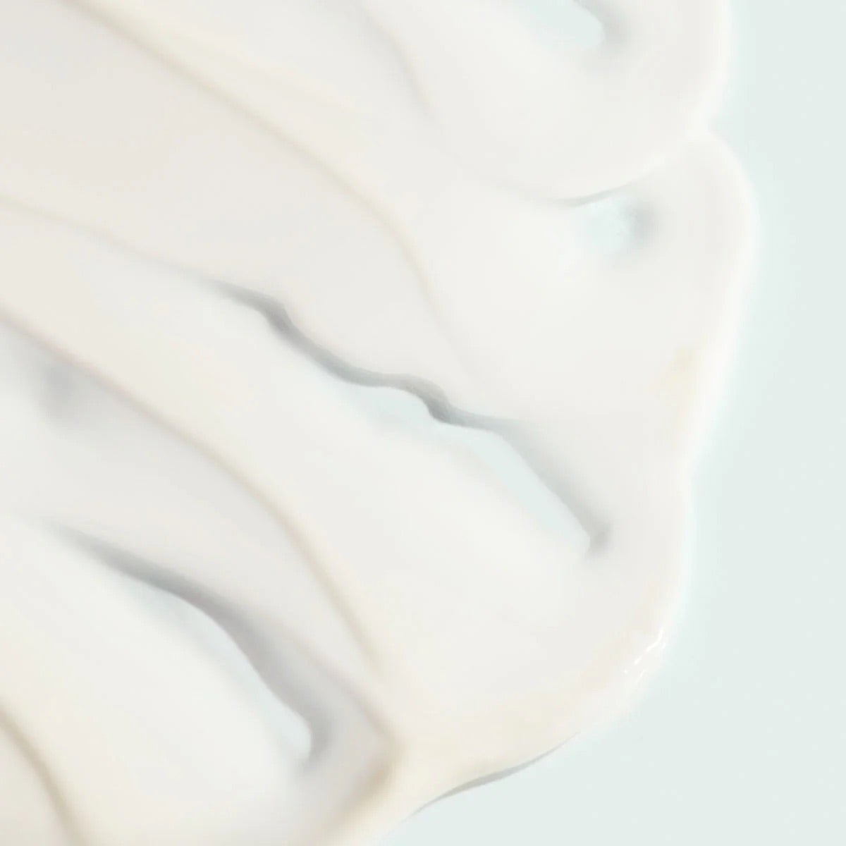 Gros plan sur la texture crémeuse blanche du sérum hydratant anti-âge VITAL C d’Image Skincare, fond pâle