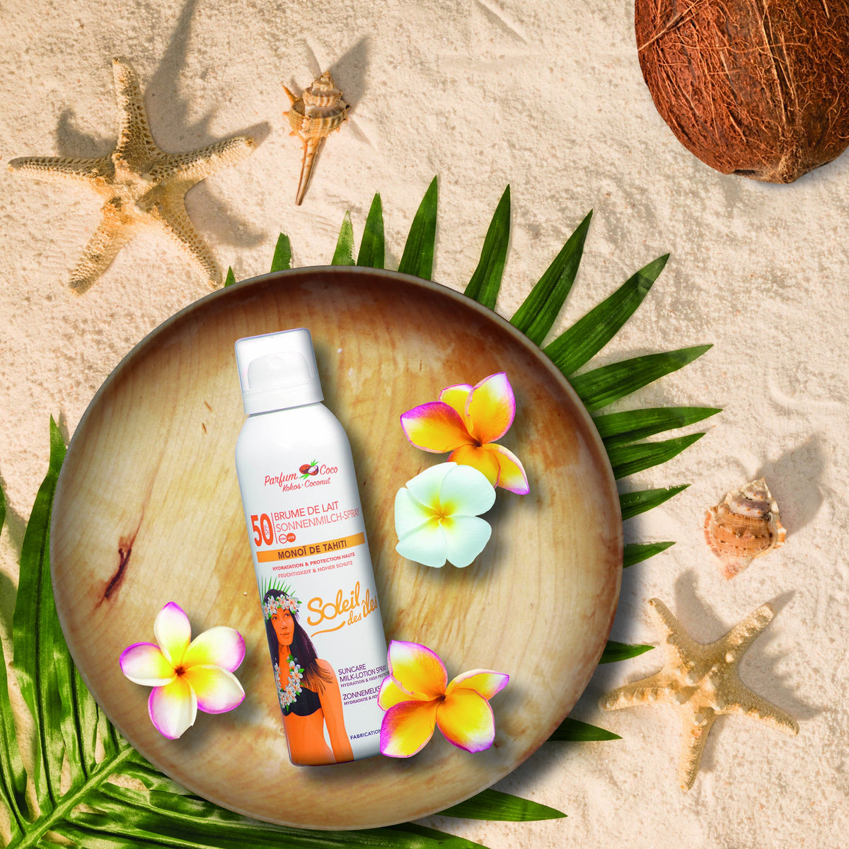 Aérosol Soleil des Îles, Brume de lait coco FPS 50 au Monoï de Tahiti, sur un plateau de bois parmi fleurs et palmes